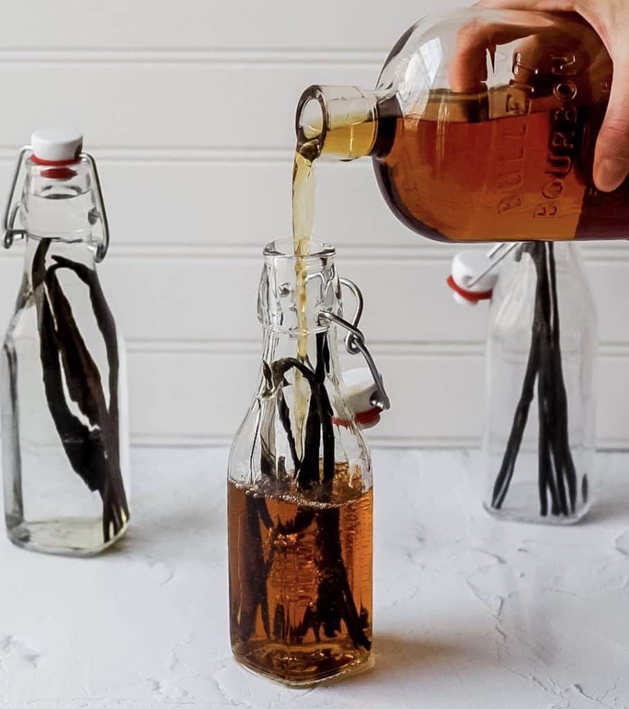pouring bourbon into glass jar with vanilla beans