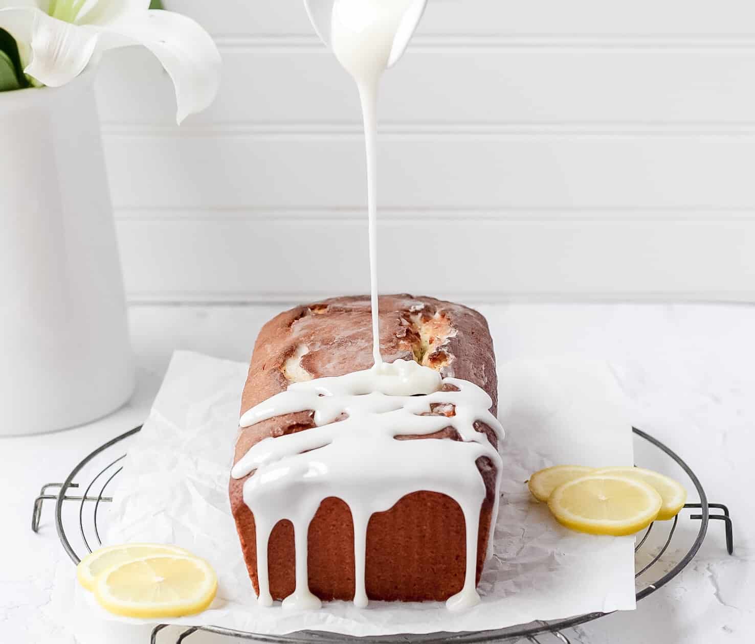 loaf cake being drizzled with lemon icing 