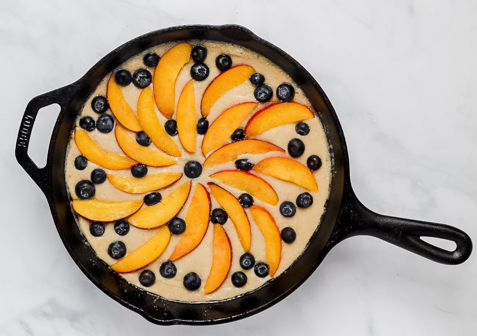 peach blueberry cobbler in cast iron pan before baking