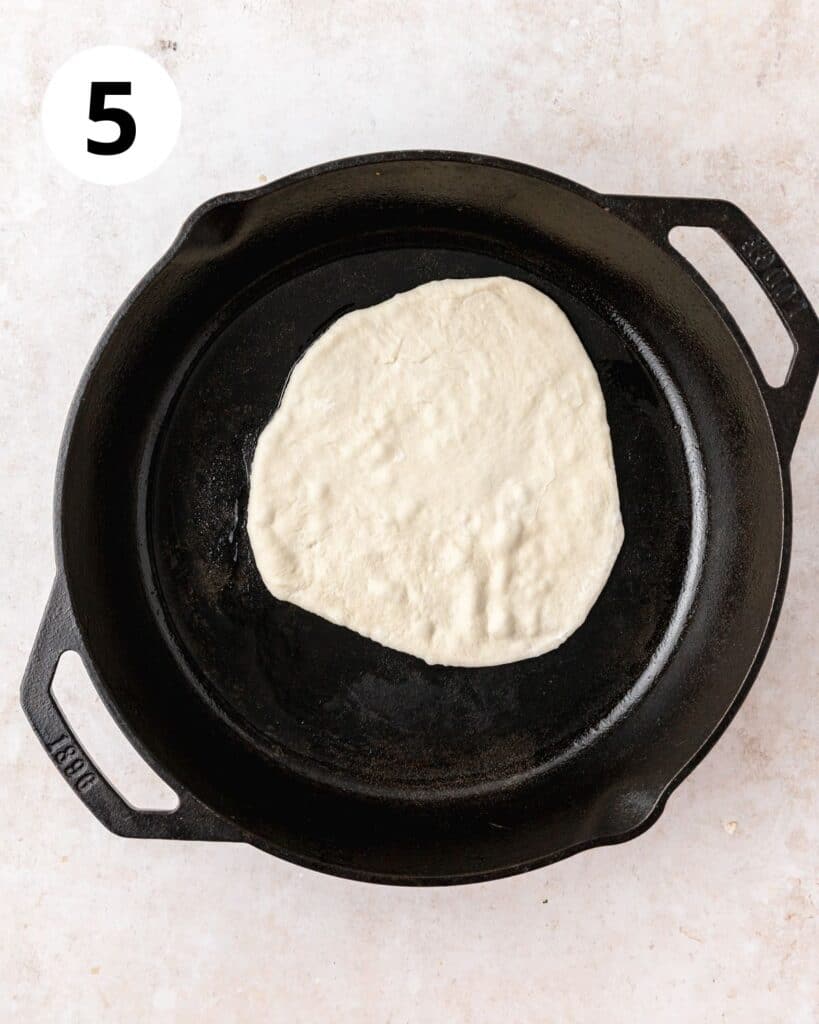 flat piece of sourdough naan dough in cast iron