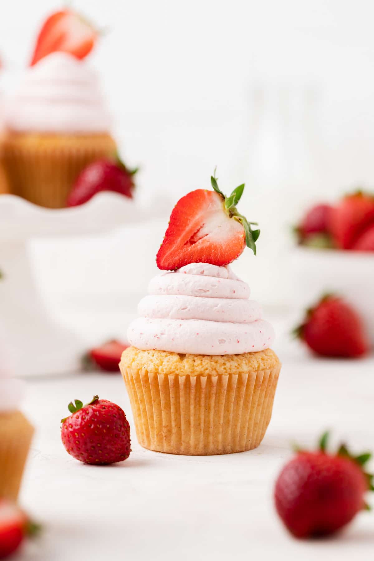 vanilla bean cupcake with pink whipped cream frosting and strawberry on top