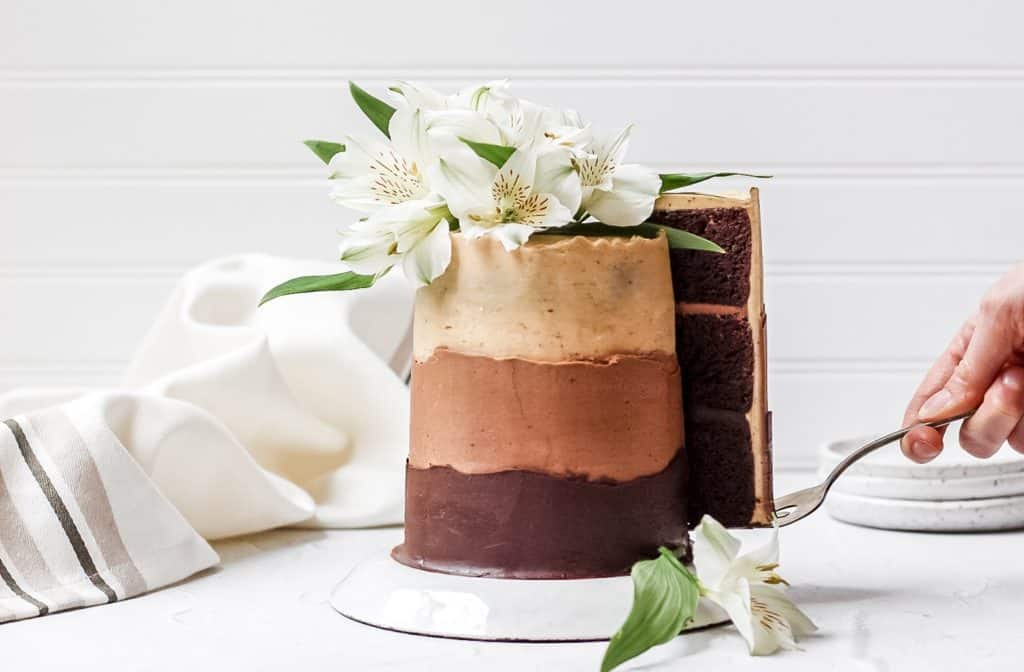 chocolate espresso ombre layer cake topped with fresh flowers with a slice being pulled out