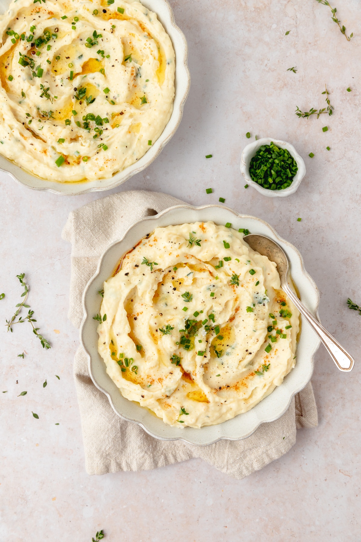 mashed potatoes with herbs and garlic in a white scalloped bowl