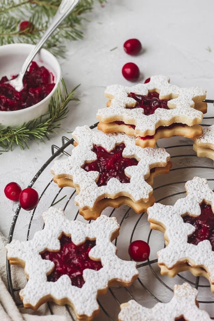 close up of cranberry linzer cookies shaped like snowflakes 