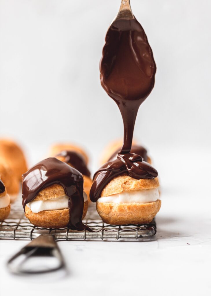 cream puffs with chocolate being drizzled on top