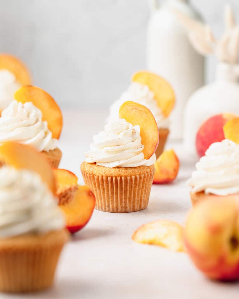 peaches and cream cupcakes with sliced peaches on top