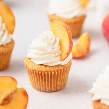peaches and cream cupcakes with sliced peaches on top