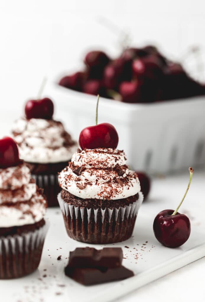black forest cupcakes with chocolate shavings and cherries on top.