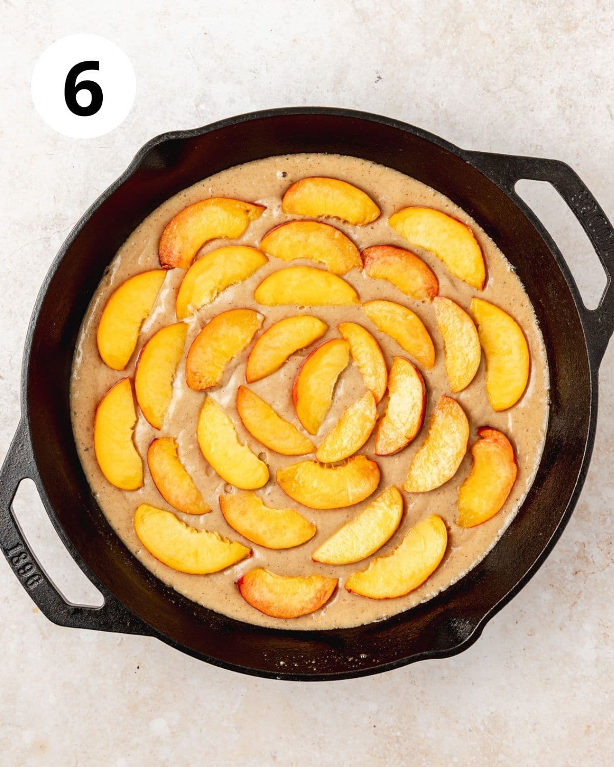 arranging peaches on top of cast iron skillet cake before baking