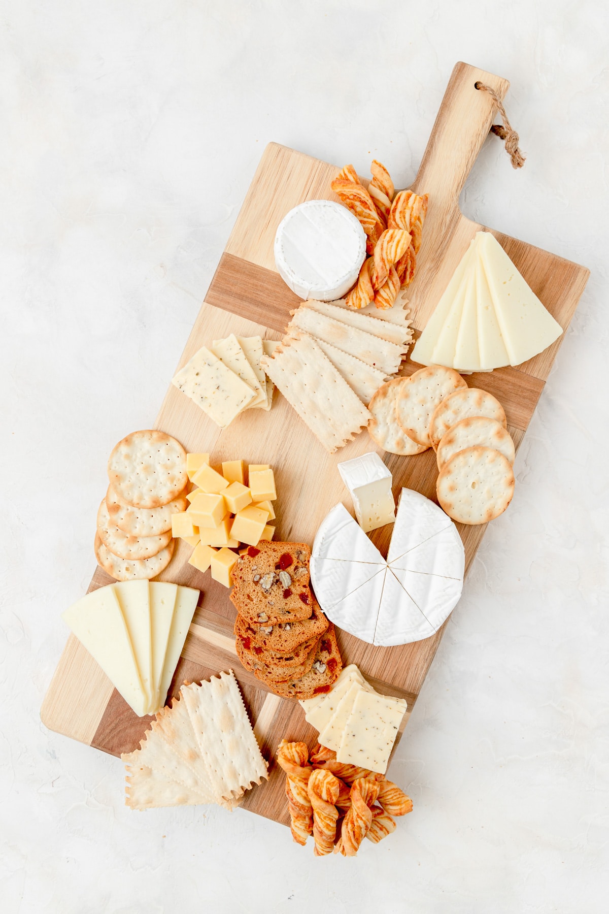 adding crackers to the board with cheese 