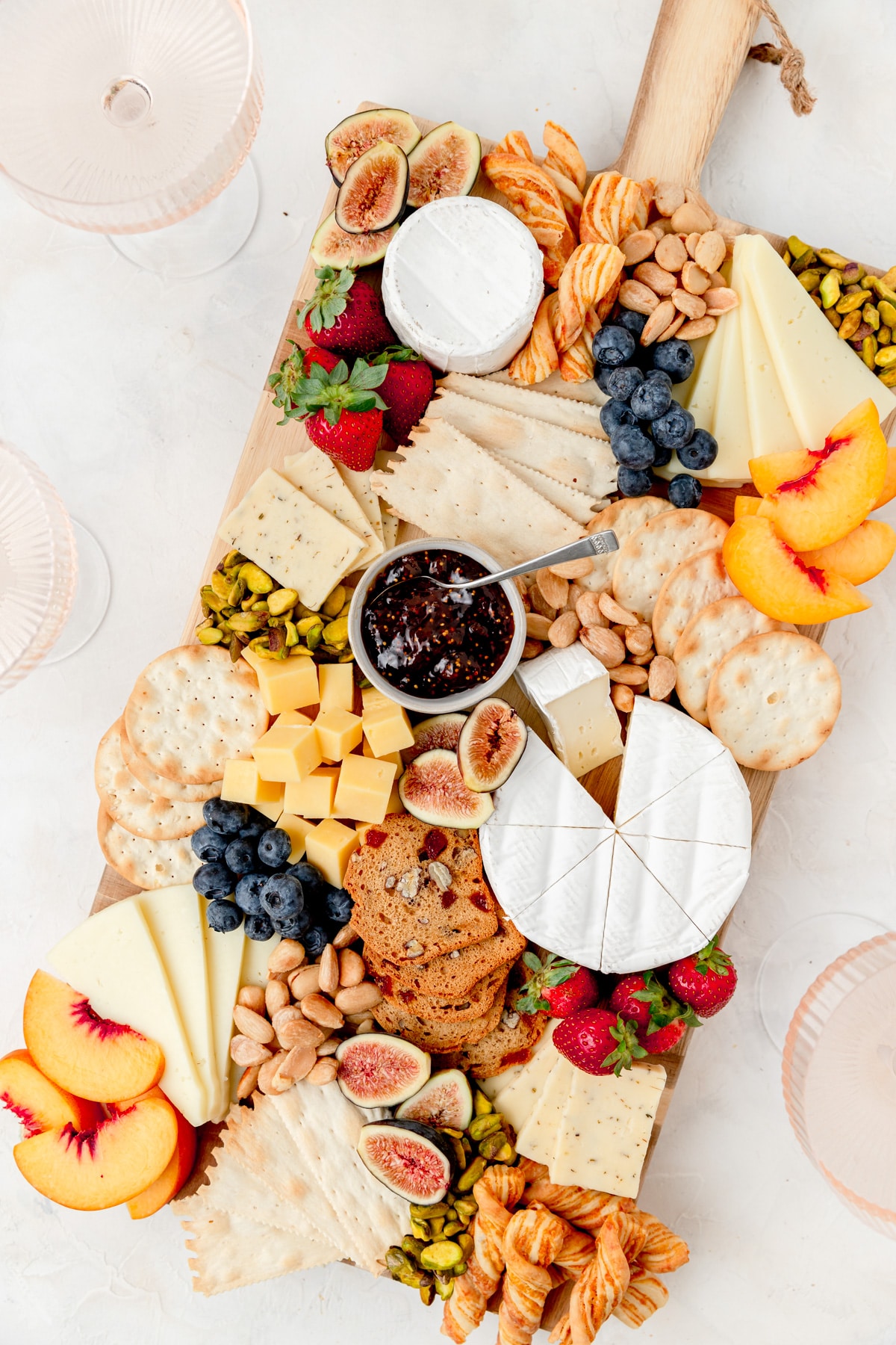 summer cheeseboard with lots of fruit and nuts on board