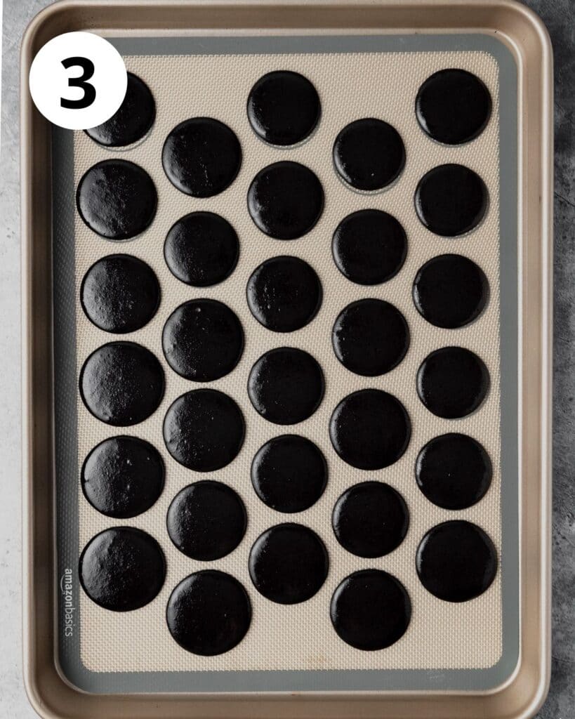 black cocoa macarons on baking sheet
