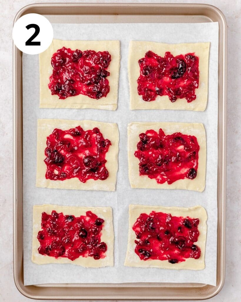 spreading cranberry sauce on puff pastry tarts