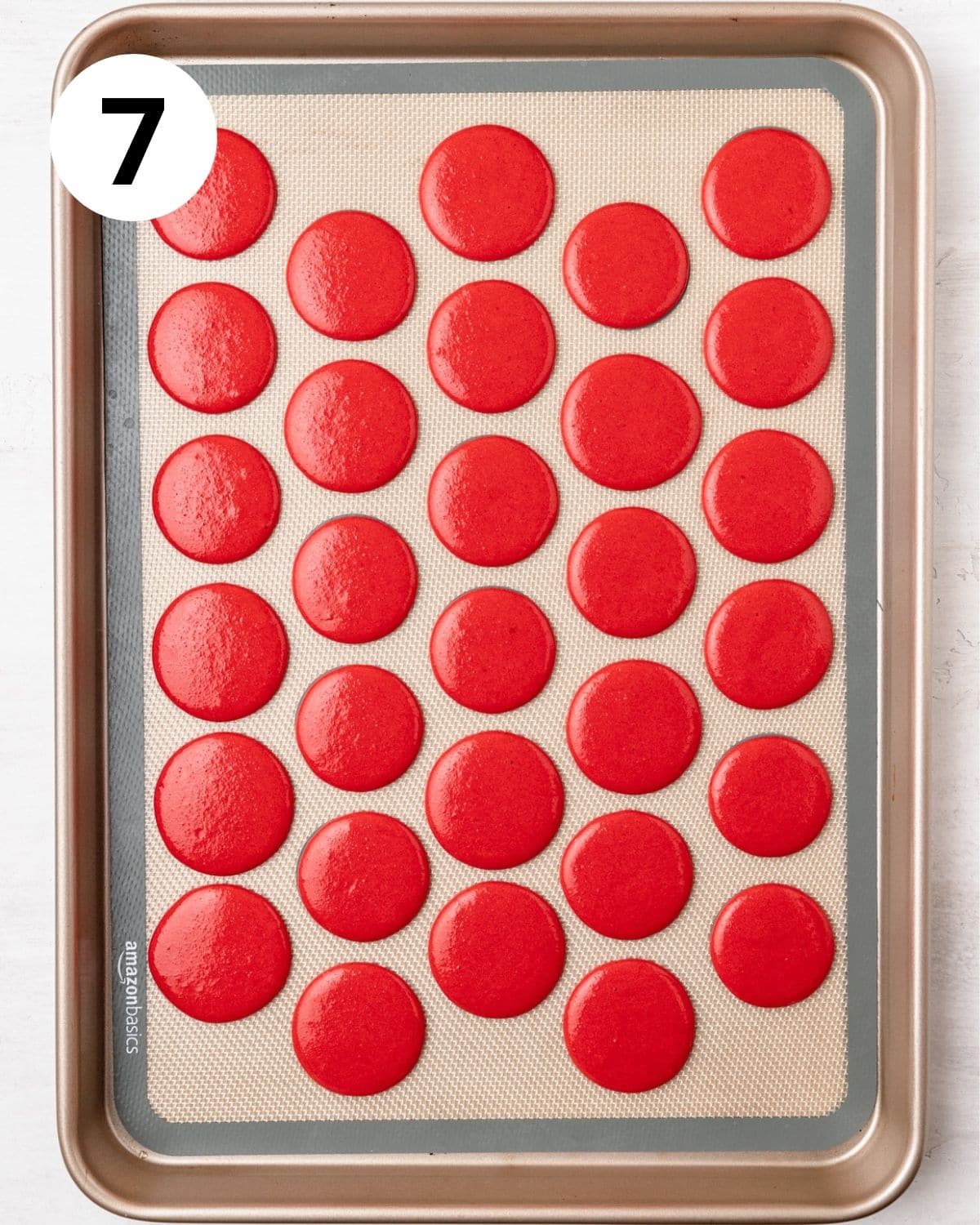 red macarons piped onto silicone mat.