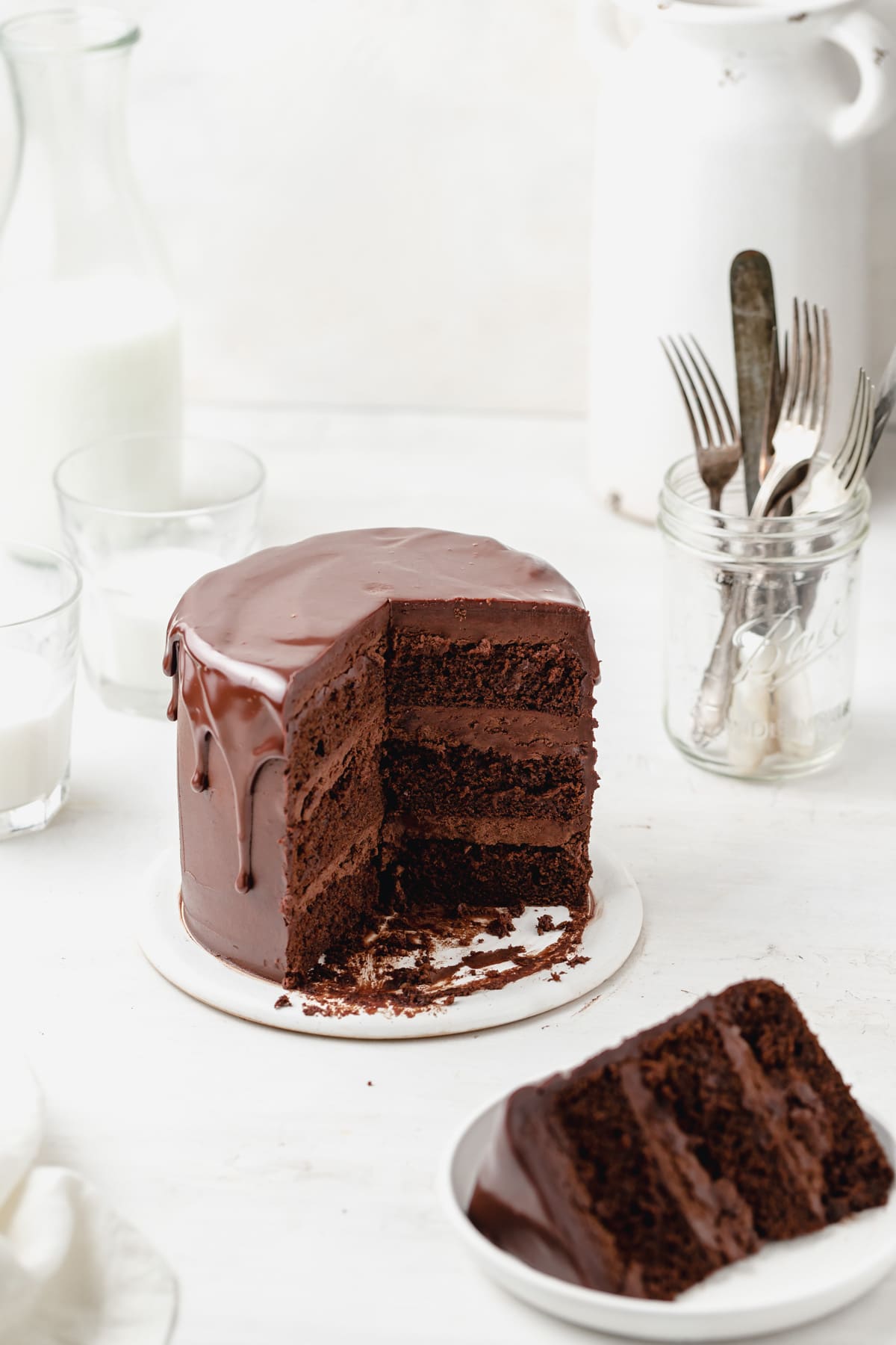 triple chocolate layer cake with chocolate ganache drip and slice cut out.