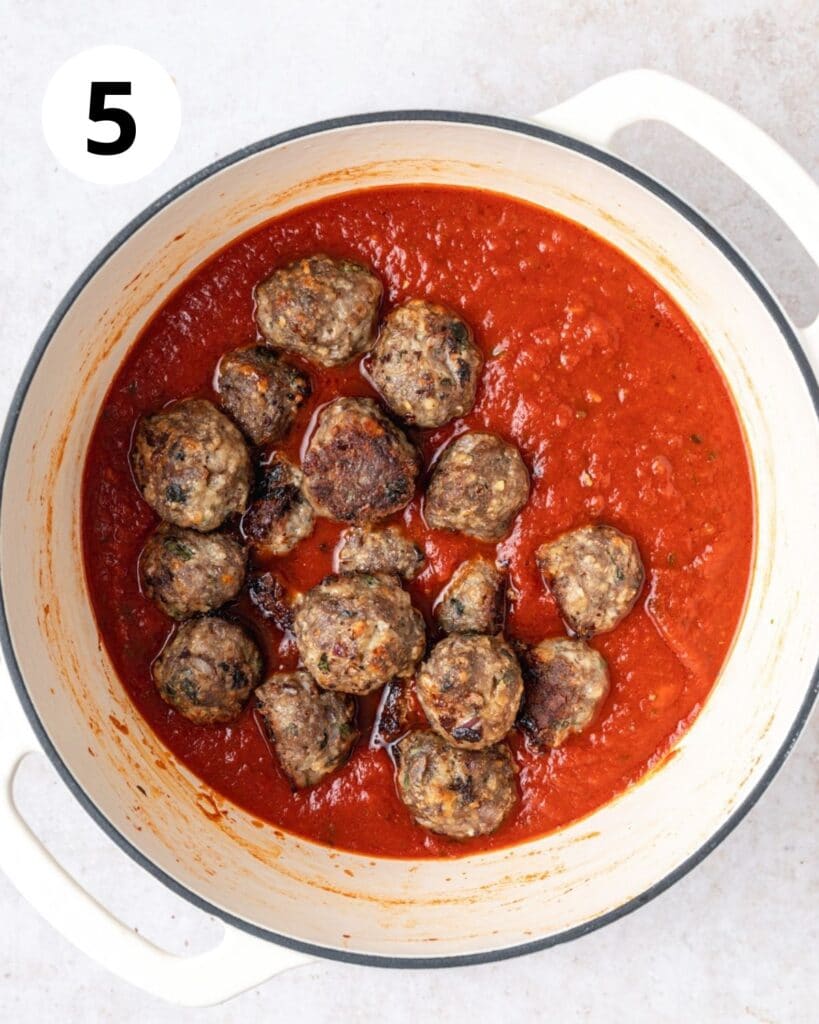 adding cooked italian meatballs to sauce.