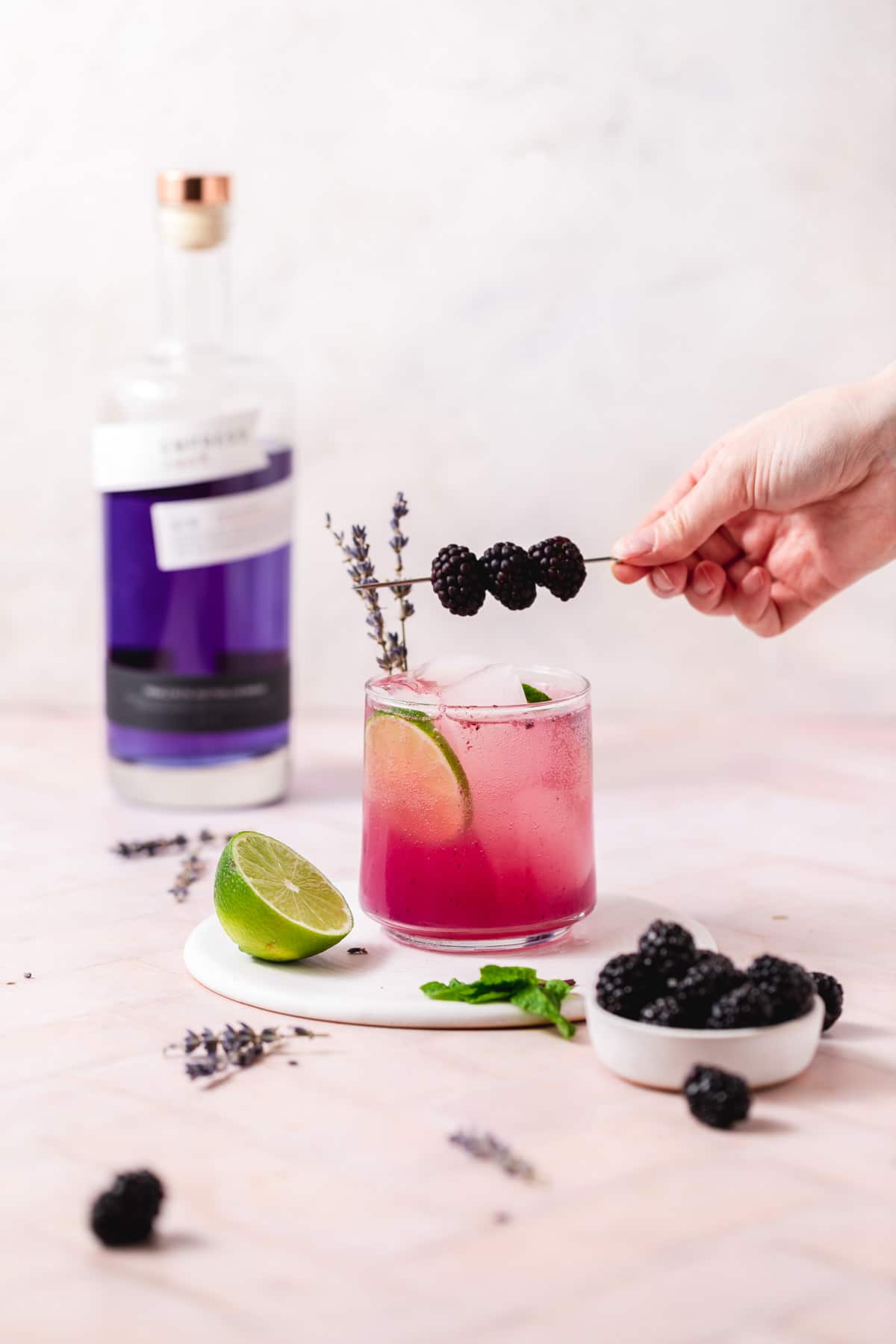 garnishing cocktail with blackberries.