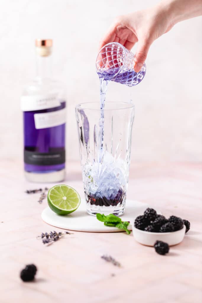 adding empress gin to cocktail shaker.