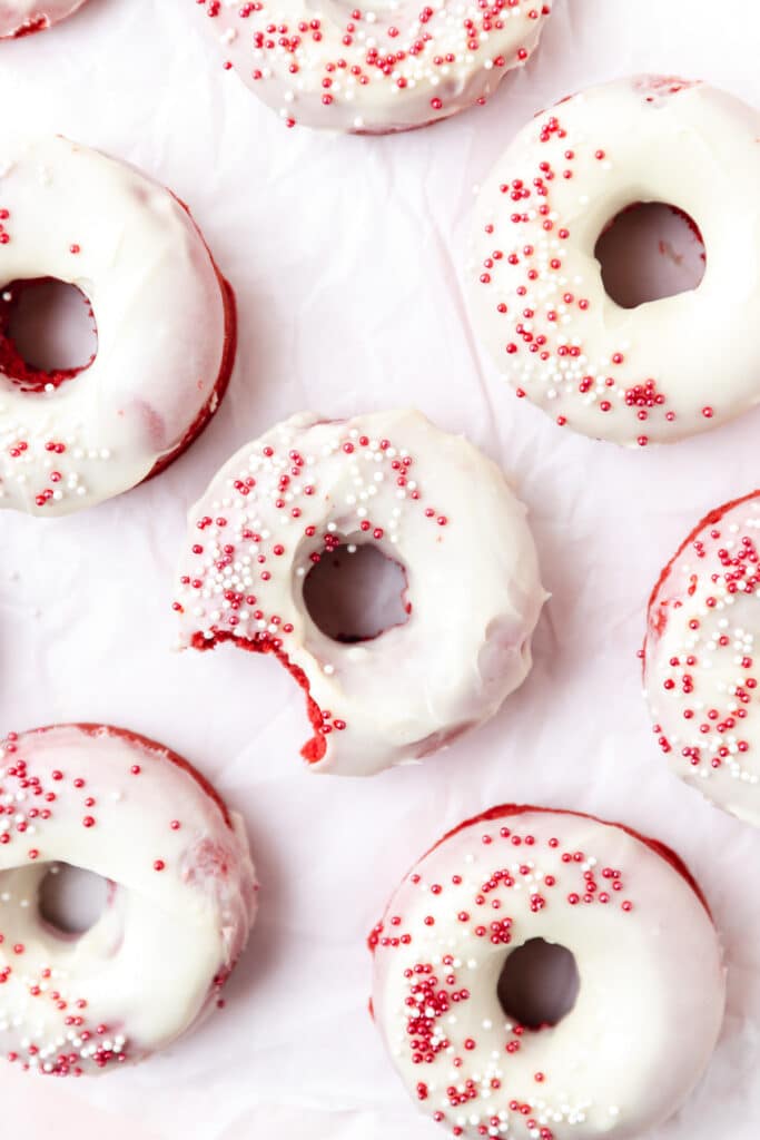 red velvet donuts with cream cheese frosting and red sprinkles.
