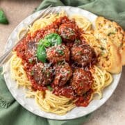 close up of italian meatballs on top of spaghetti.