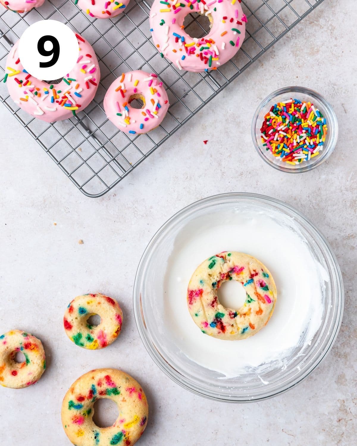 dipping funfetti baked donuts in glaze.