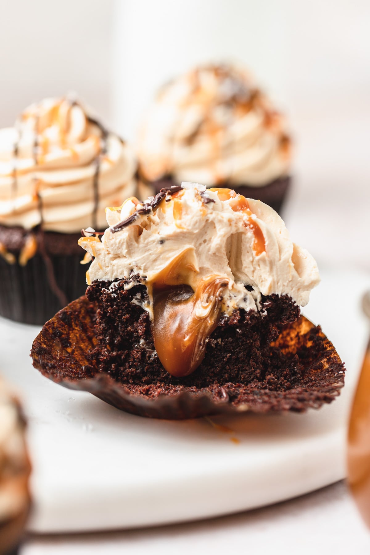 chocolate caramel cupcakes cut in half with caramel oozing out.