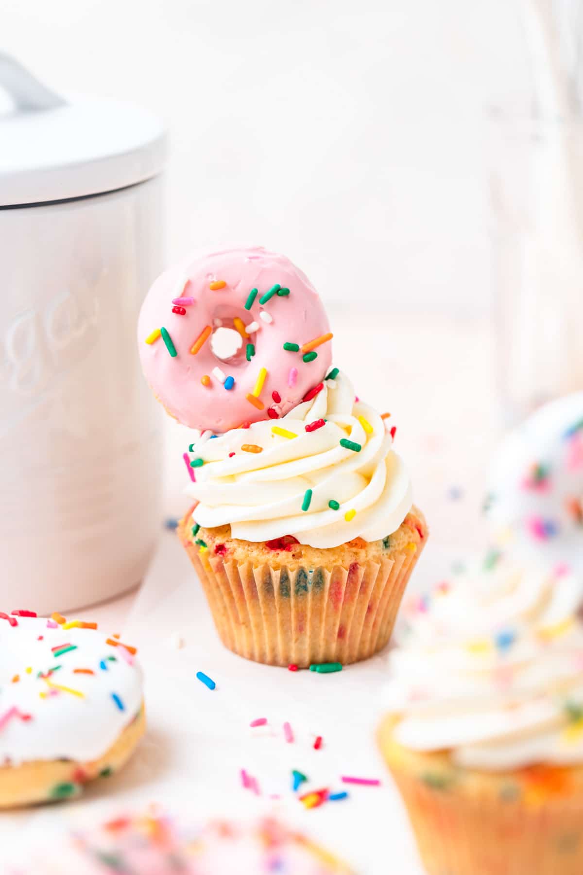 vanilla cupcakes with mini funfetti donut cupcakes on top.