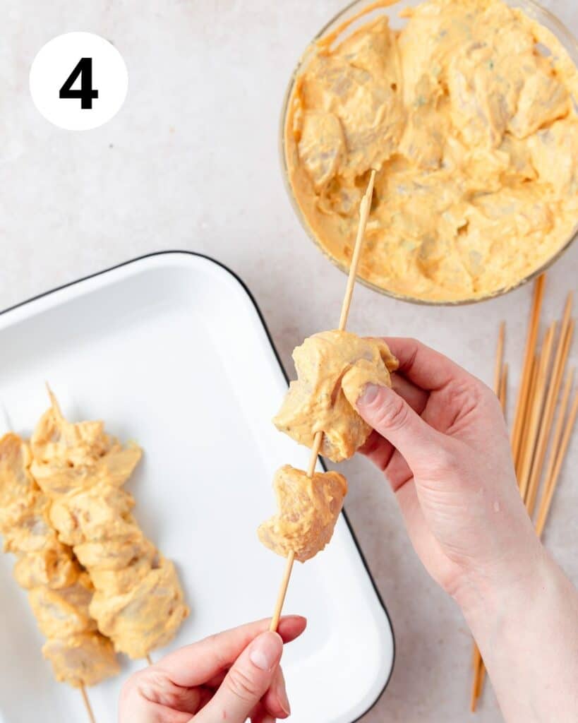 putting chunks of chicken onto skewers.