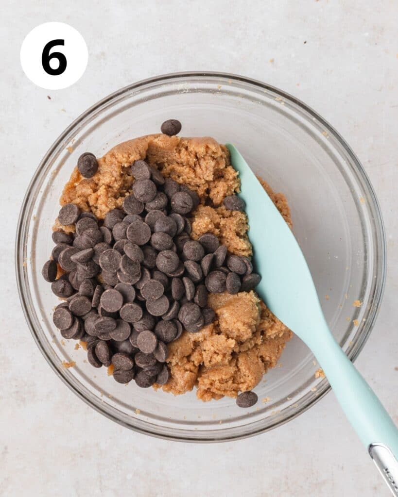 adding chocolate chips to almond butter cookie dough.