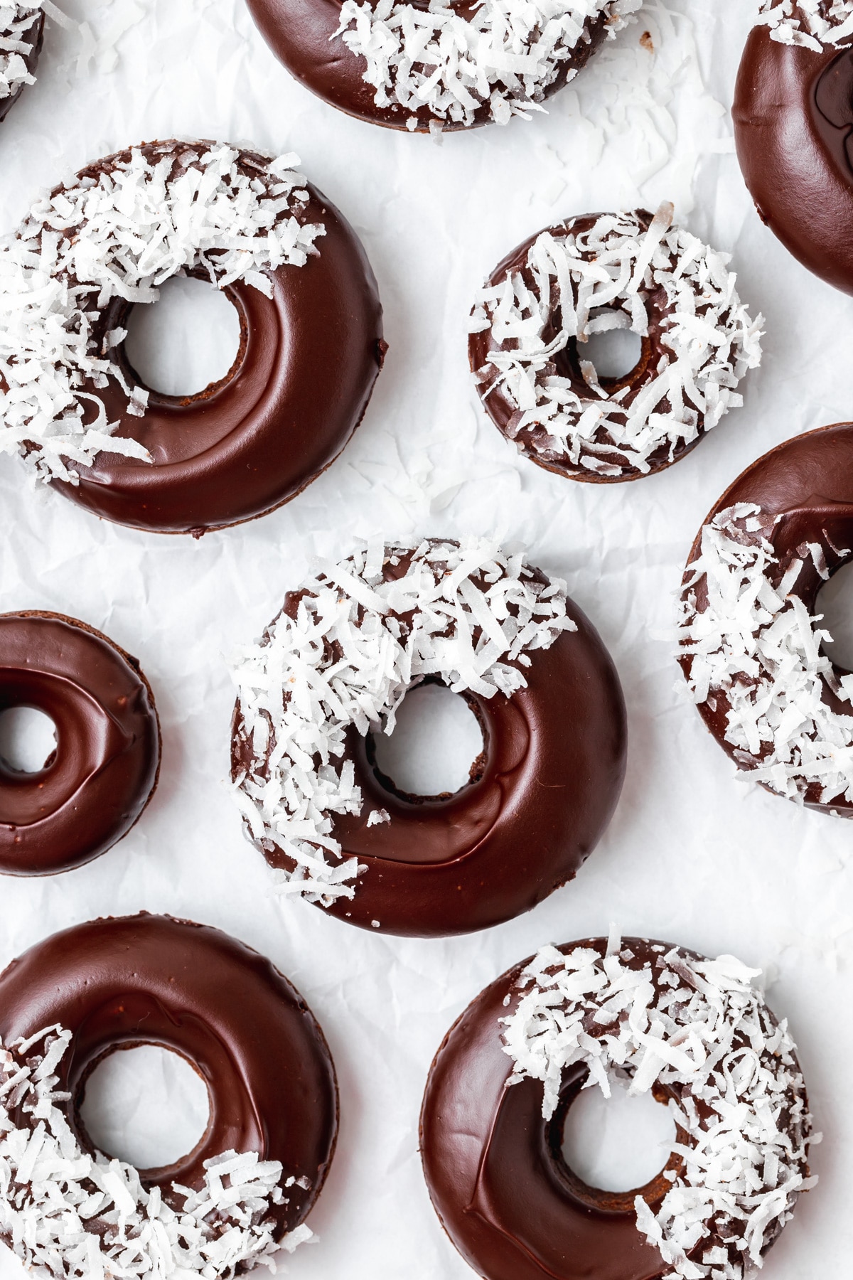baked chocolate donuts with coconut flakes on top.