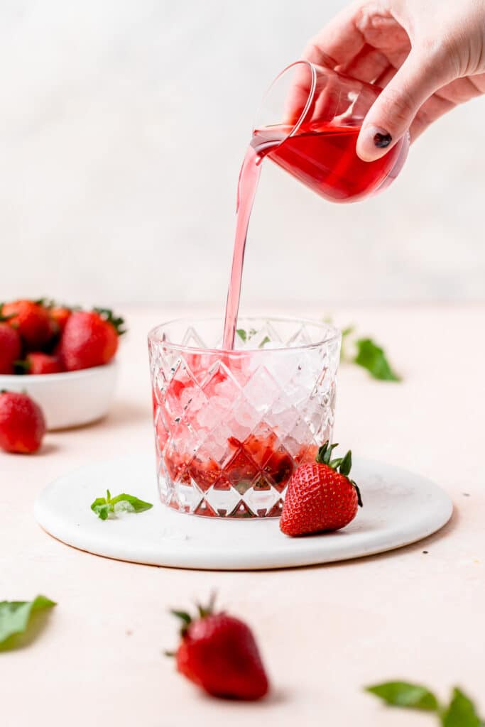 pouring strawberry simple syrup into mojito.