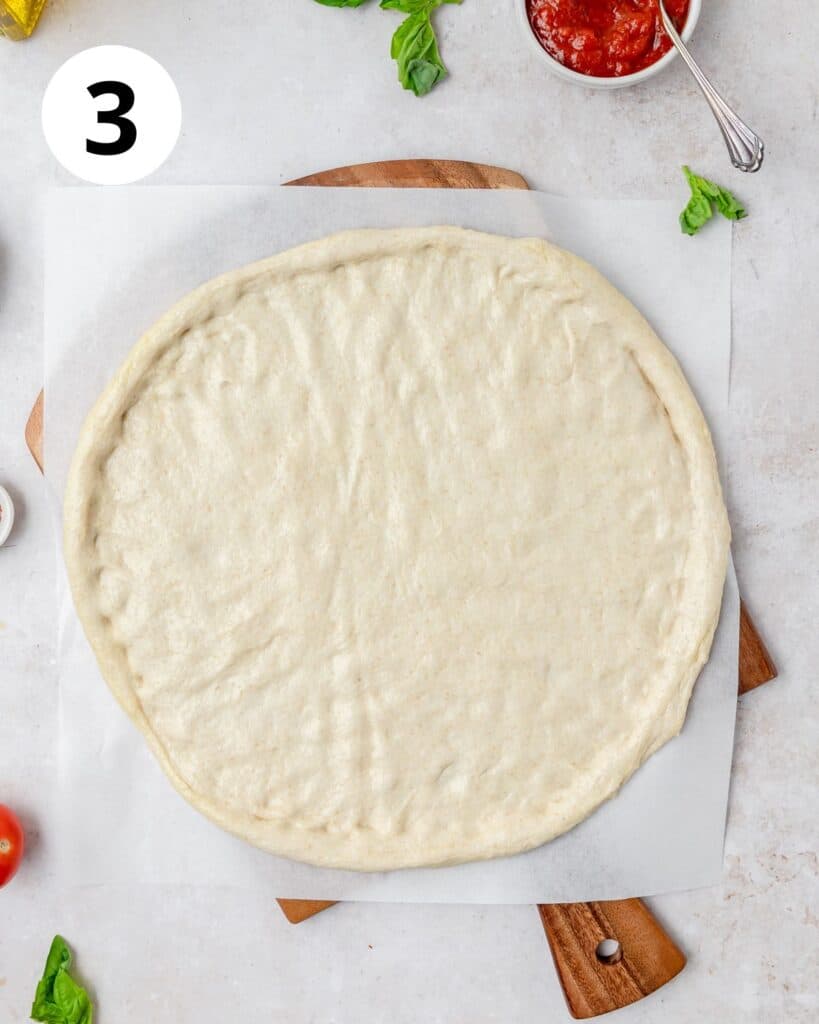 sourdough pizza dough pressed out into large thin circle.