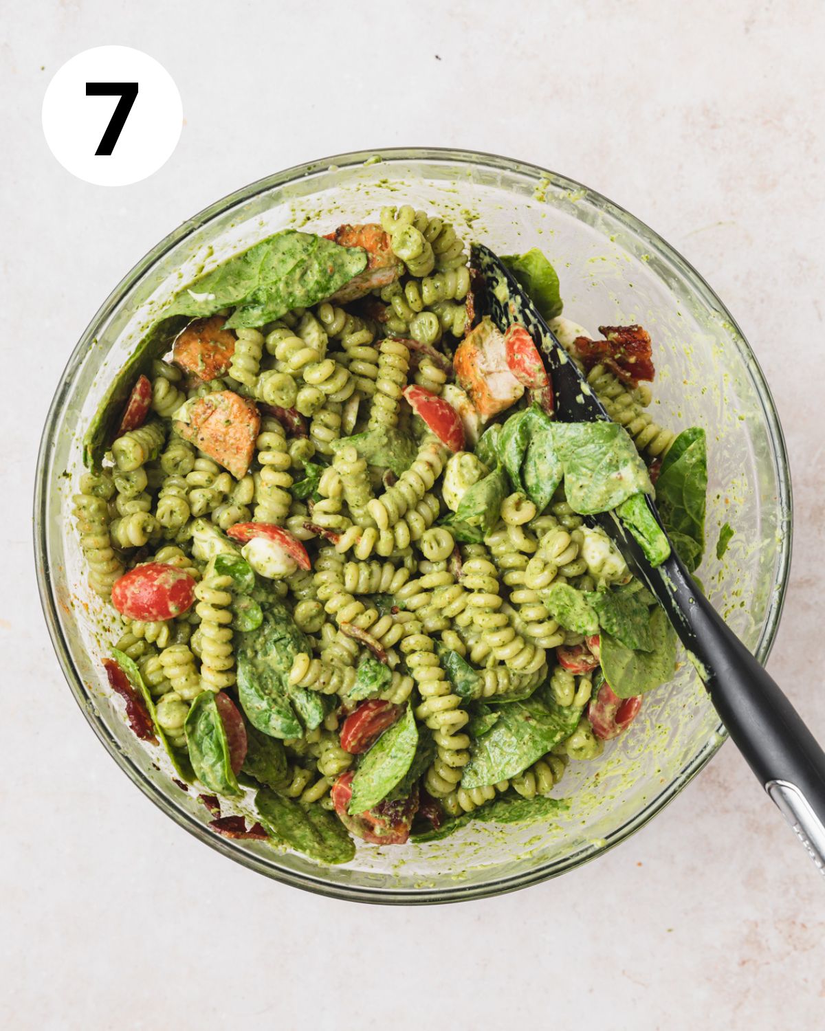 chicken pesto pasta salad mixed together in bowl.