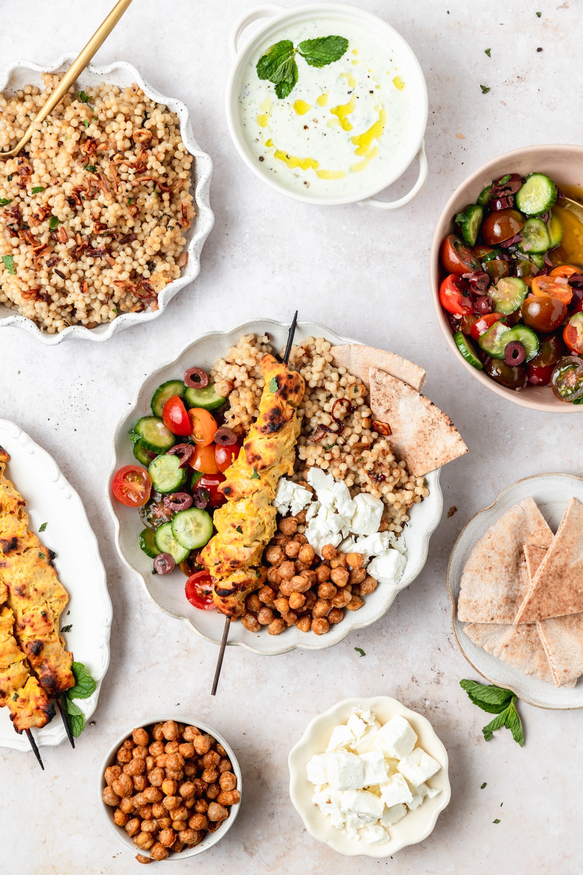 greek chicken couscous bowls with crispy chickpeas and tomato cucumber salad.
