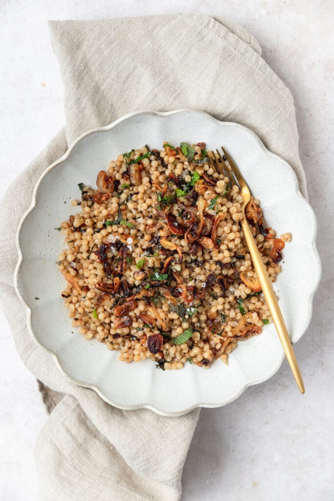 bowl of toasted pearl couscous with crispy shallots.
