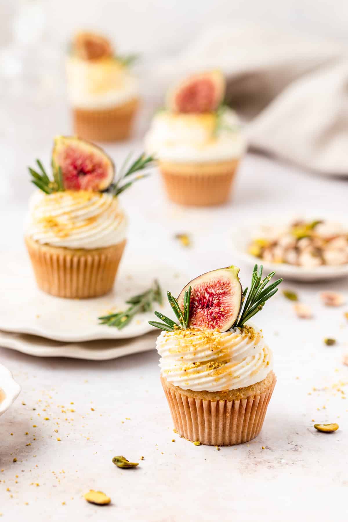 fig olive oil cupcakes topped with mascarpone frosting, fresh figs, ground pistachios, and rosemary.