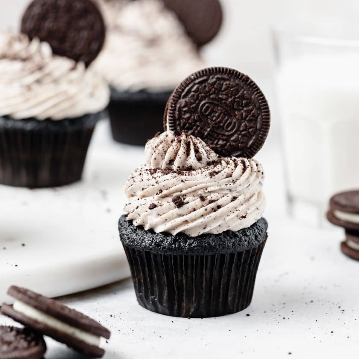 close up shot of cookies and cream cupcakes with oreo on top.