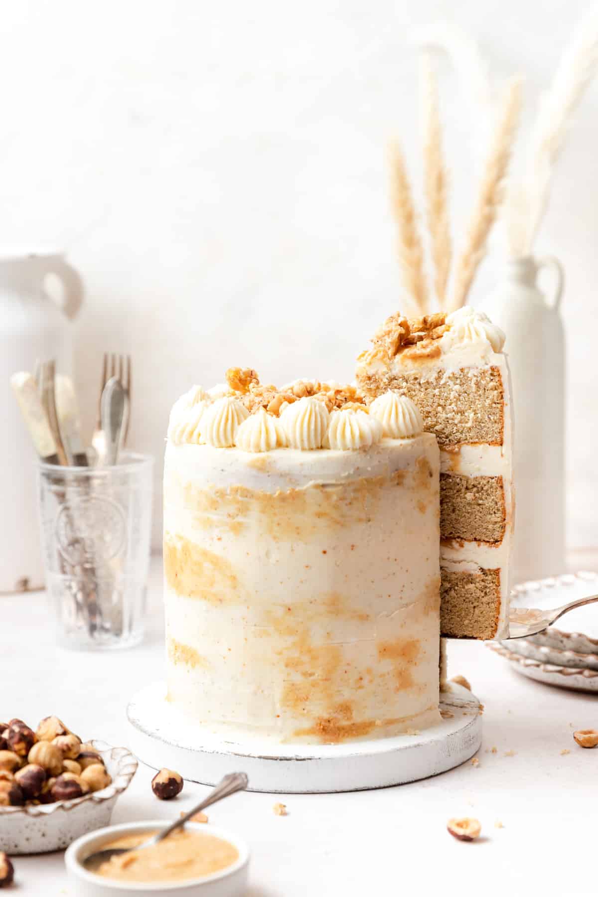 three layer brown butter hazelnut praline cake with slice cut out.