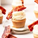 close up shot of maple bacon cupcakes topped with candied bacon.