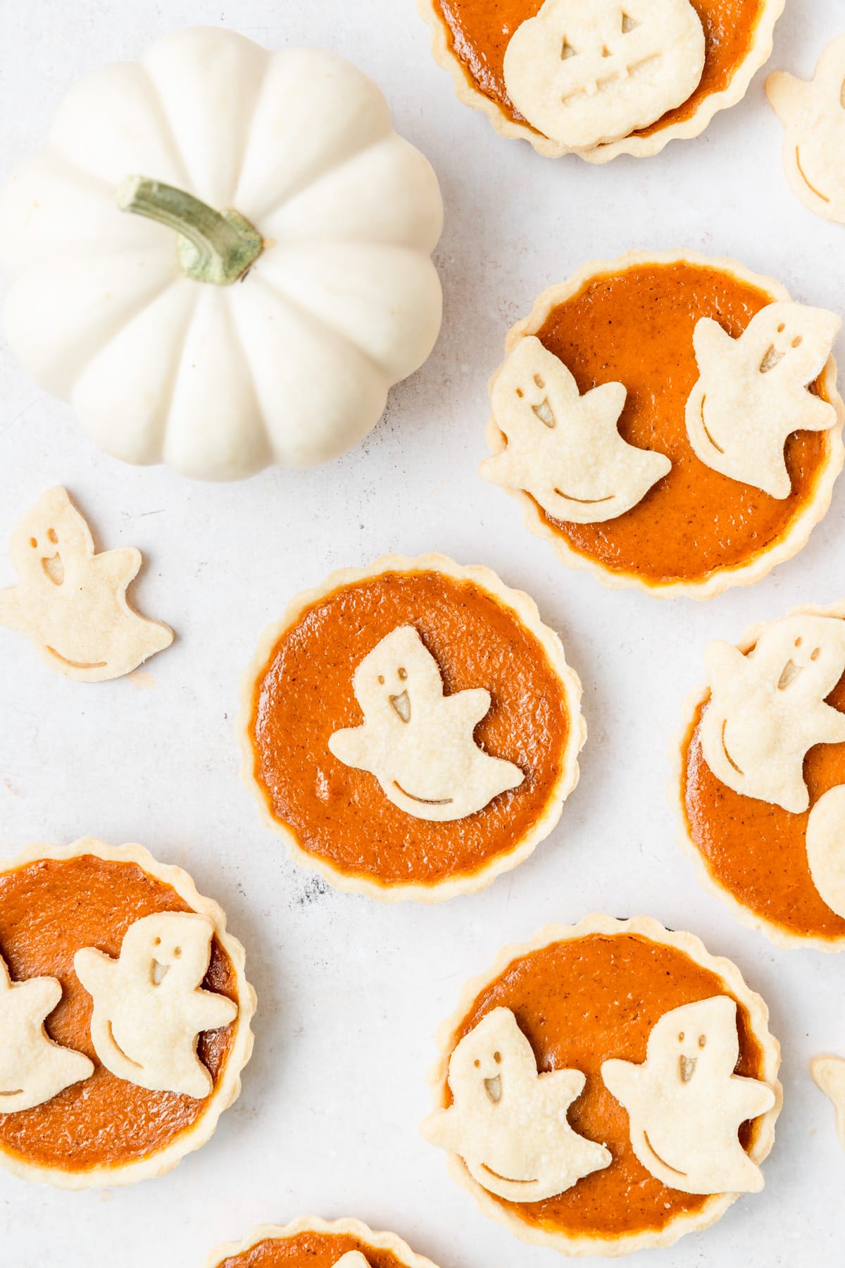 mini pumpkin pies with ghost cutouts for halloween.