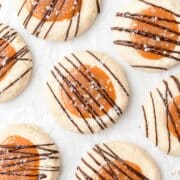 close up shot of caramel thumbprint cookies with chocolate drizzle.