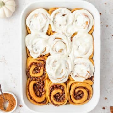 close up shot of pumpkin spice cinnamon rolls with maple and pecans.