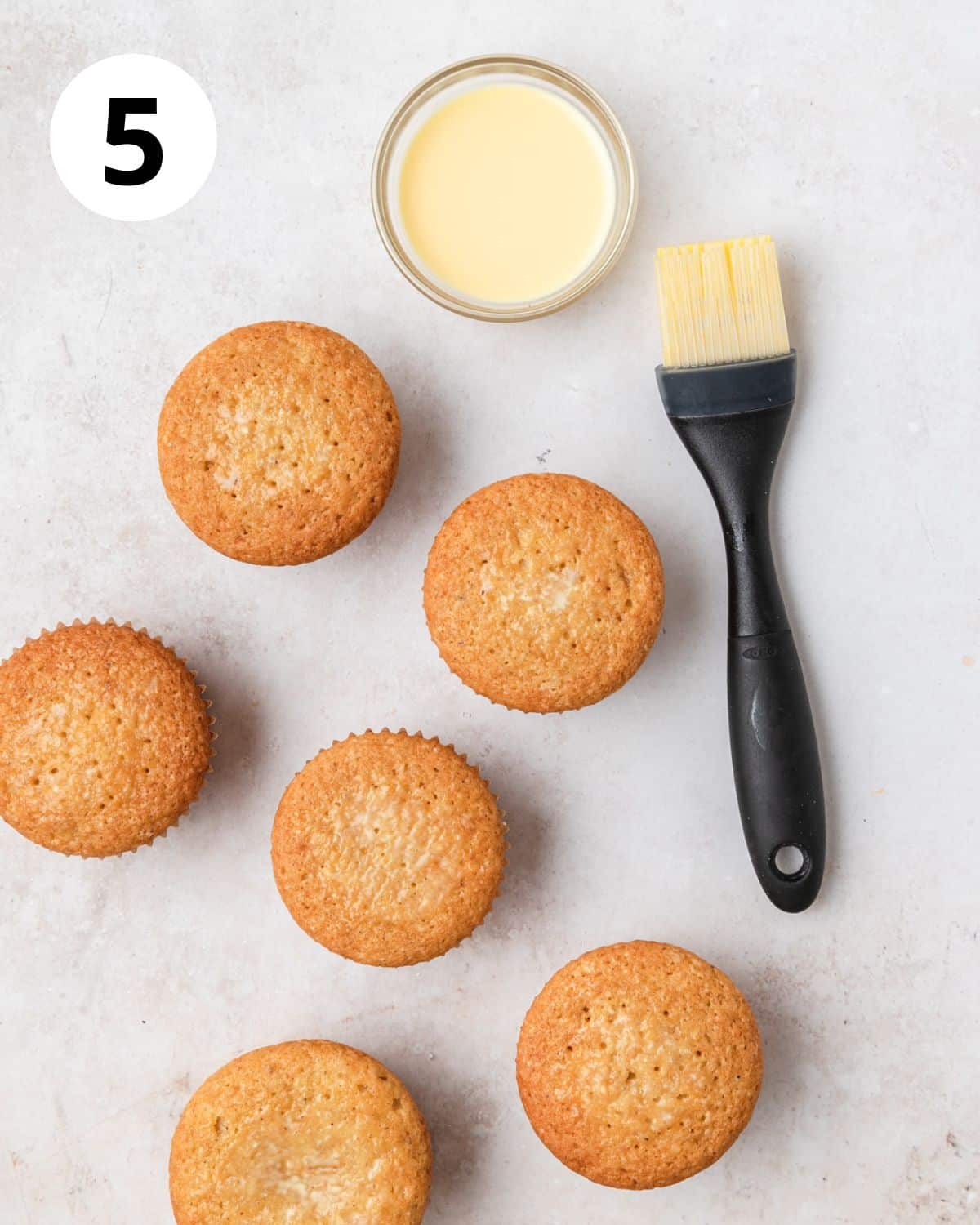 brushing tops of cupcakes with eggnog.