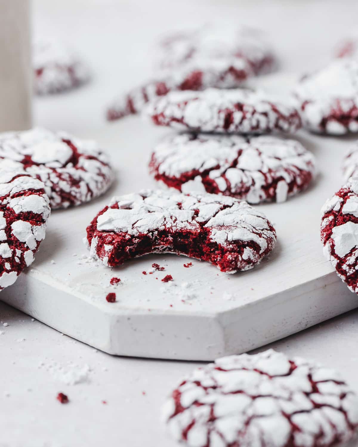 bite taken out of red velvet crinkle cookies rolled in powdered sugar.