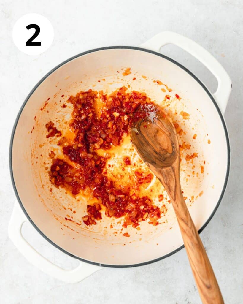 adding in tomato paste to soup.