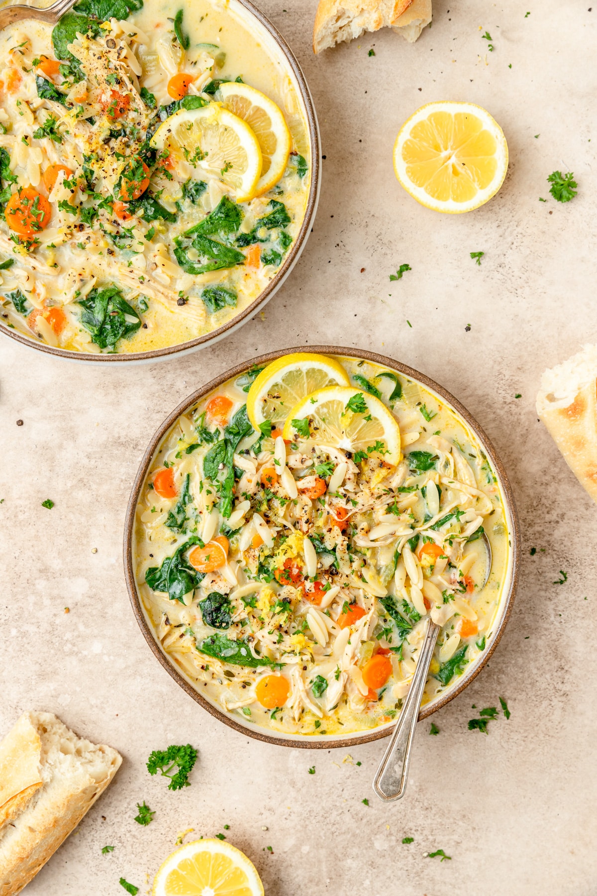 two bowls of creamy lemon chicken orzo soup with spinach.