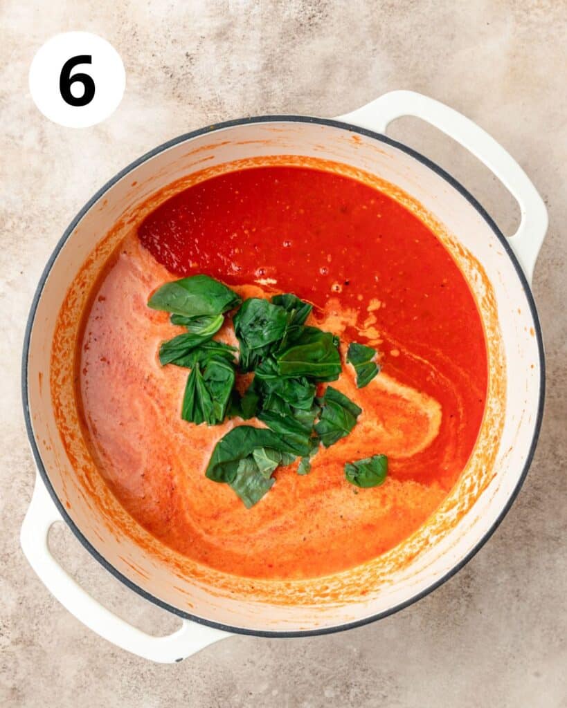 adding heavy cream and fresh basil to tomato soup.