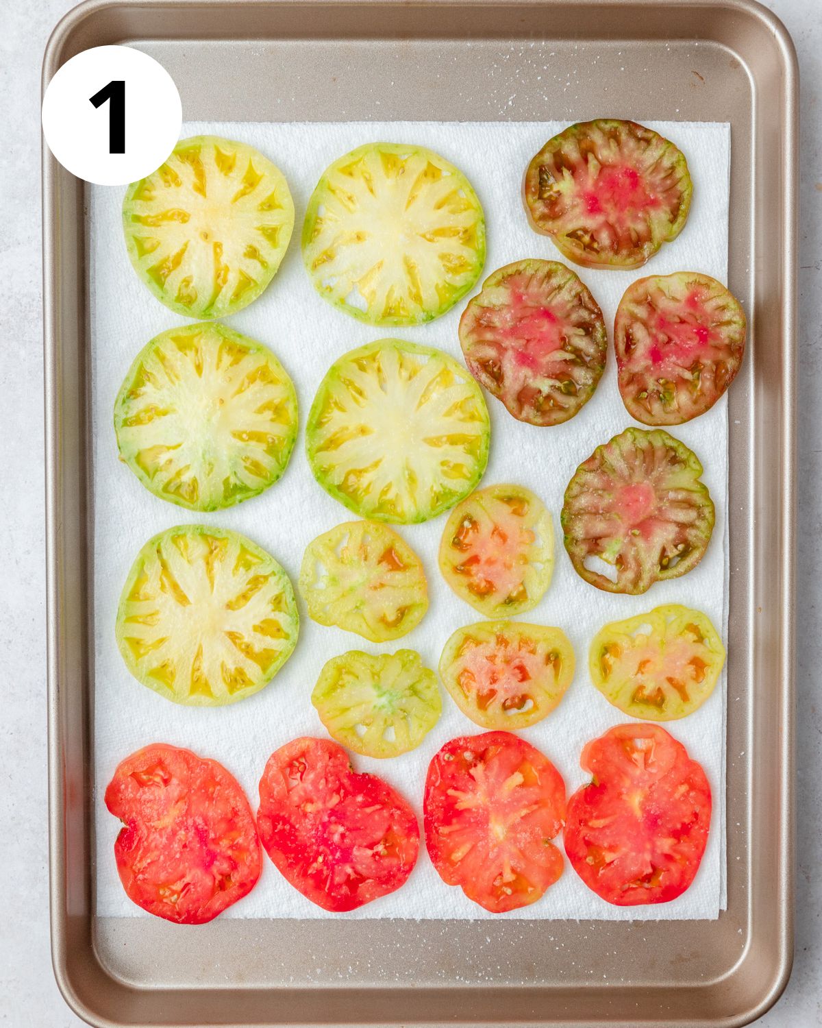 sliced heirloom tomatoes being salted to remove moisture.