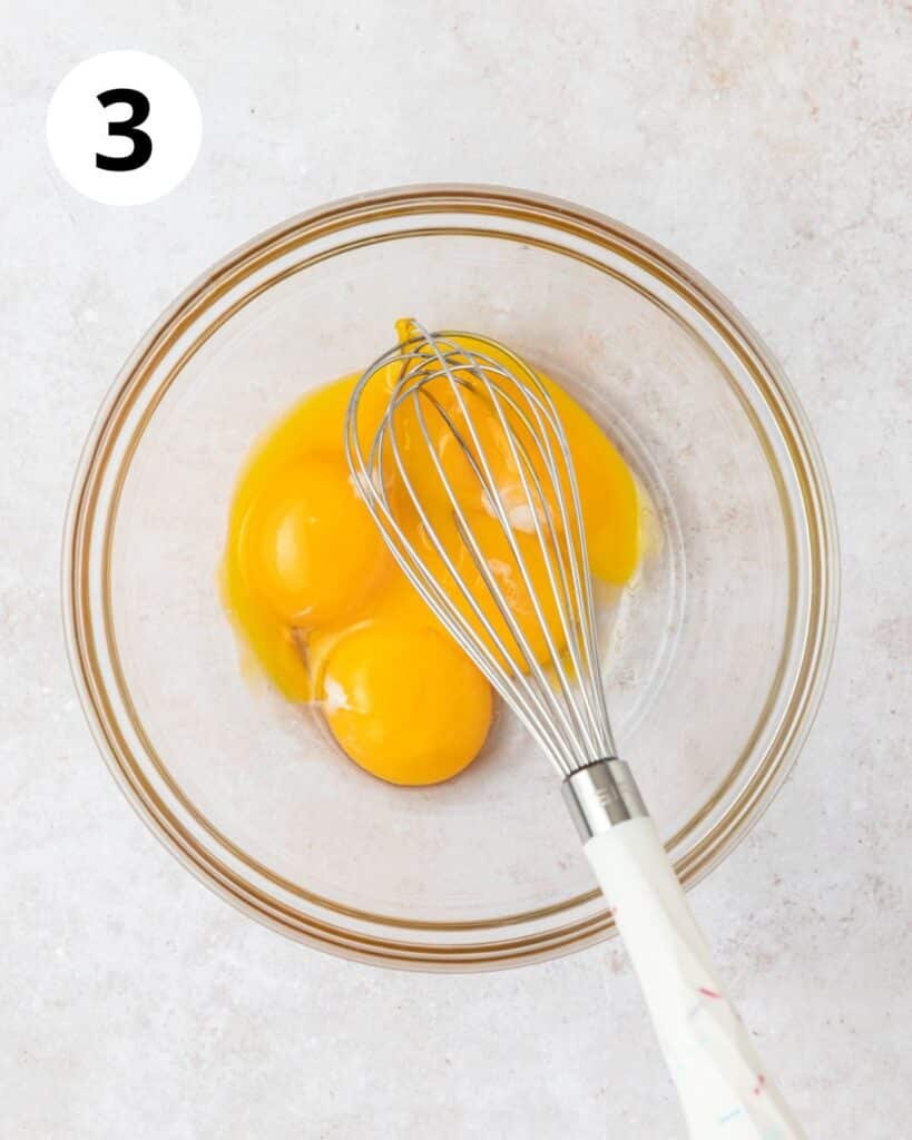 whisking egg yolks in small bowl.