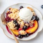 close up shot of peach blueberry cobbler with vanilla ice cream.